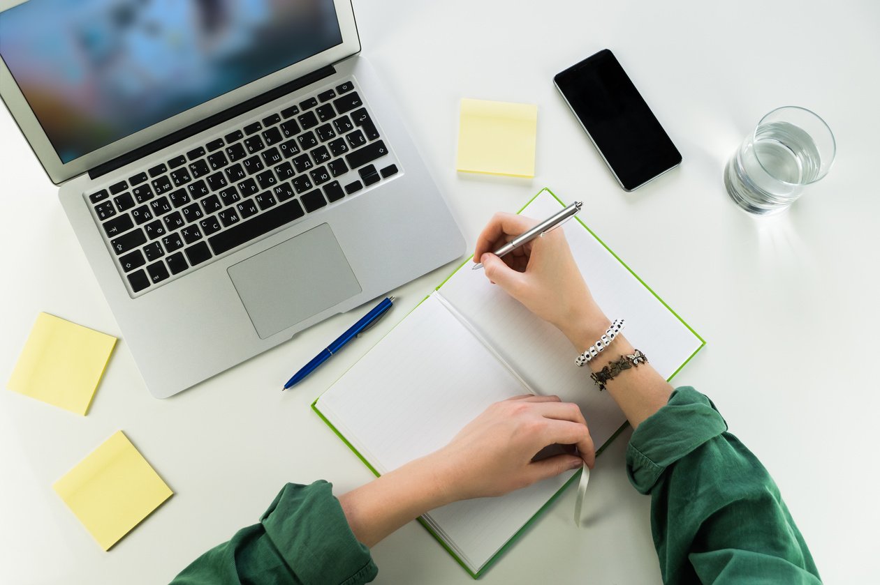 Woman Working at Desk with Notepad and Laptop 